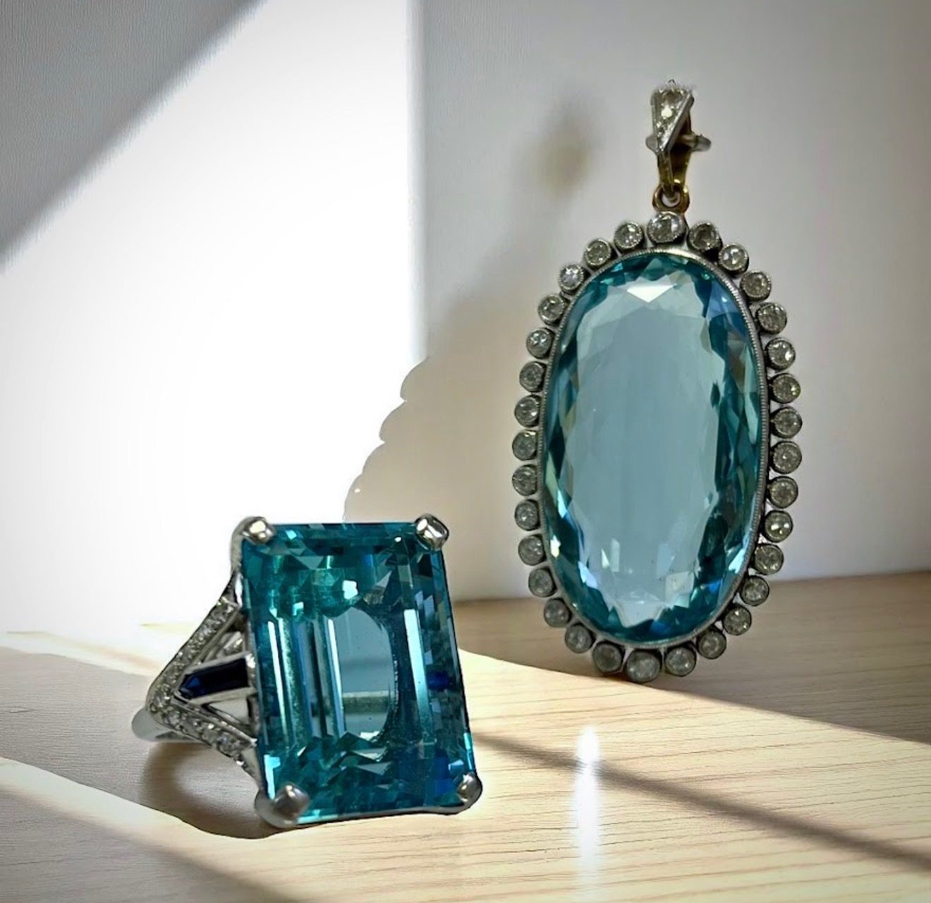 A large aquamarine ring and an oval aquamarine pendant framed in diamonds