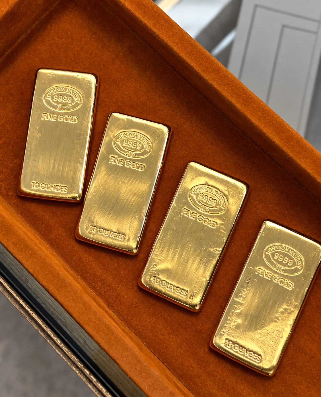 Four 10-ounce Johnson Matthey fine gold bars on a velvet tray