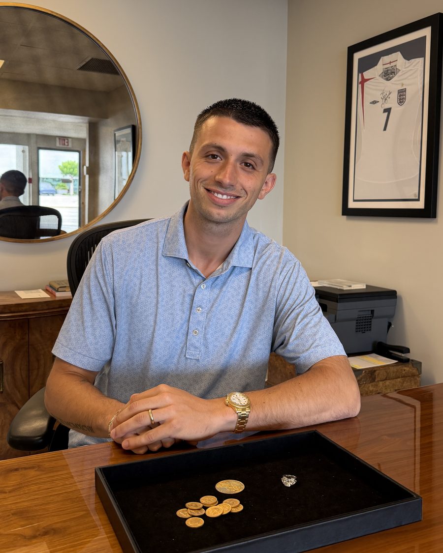 Max Dickson at his desk with a tray of gold coins and a diamond ring